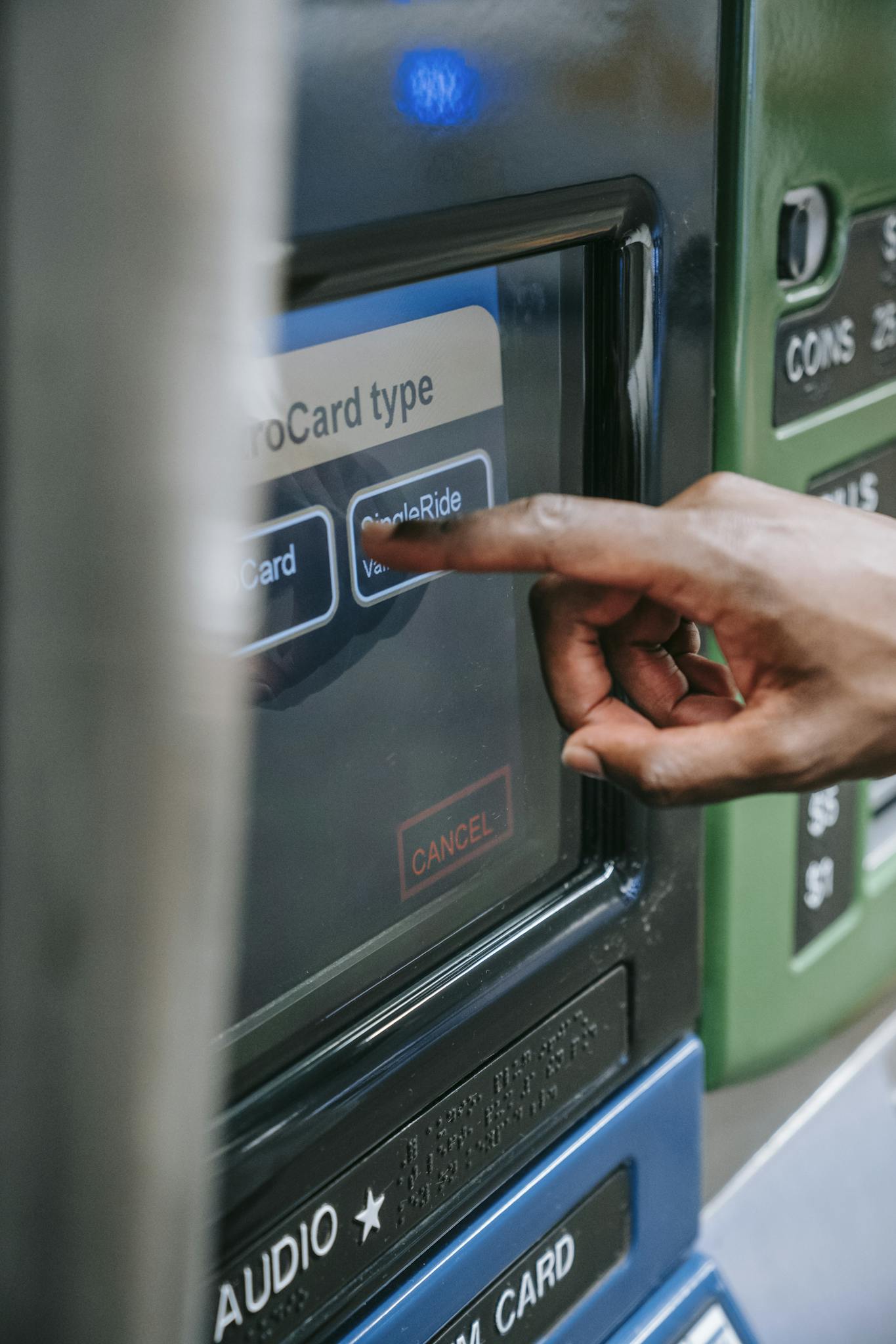 Close-up of a hand using a touchscreen on an ATM or ticket machine to select a card type.
